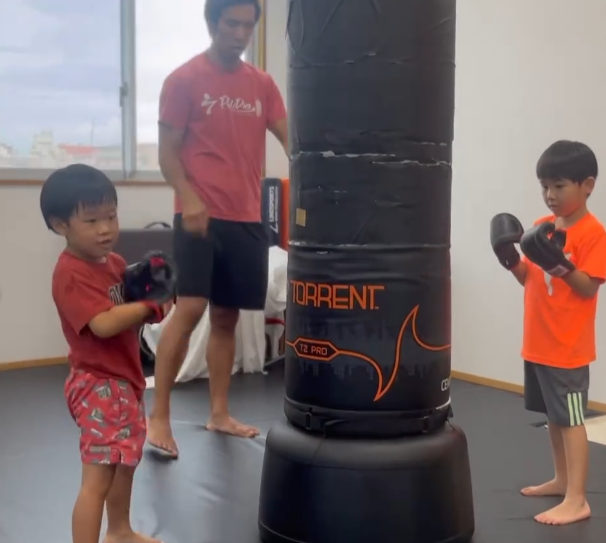 トレーナーに見守られながらサンドバッグを練習するキッズクラス